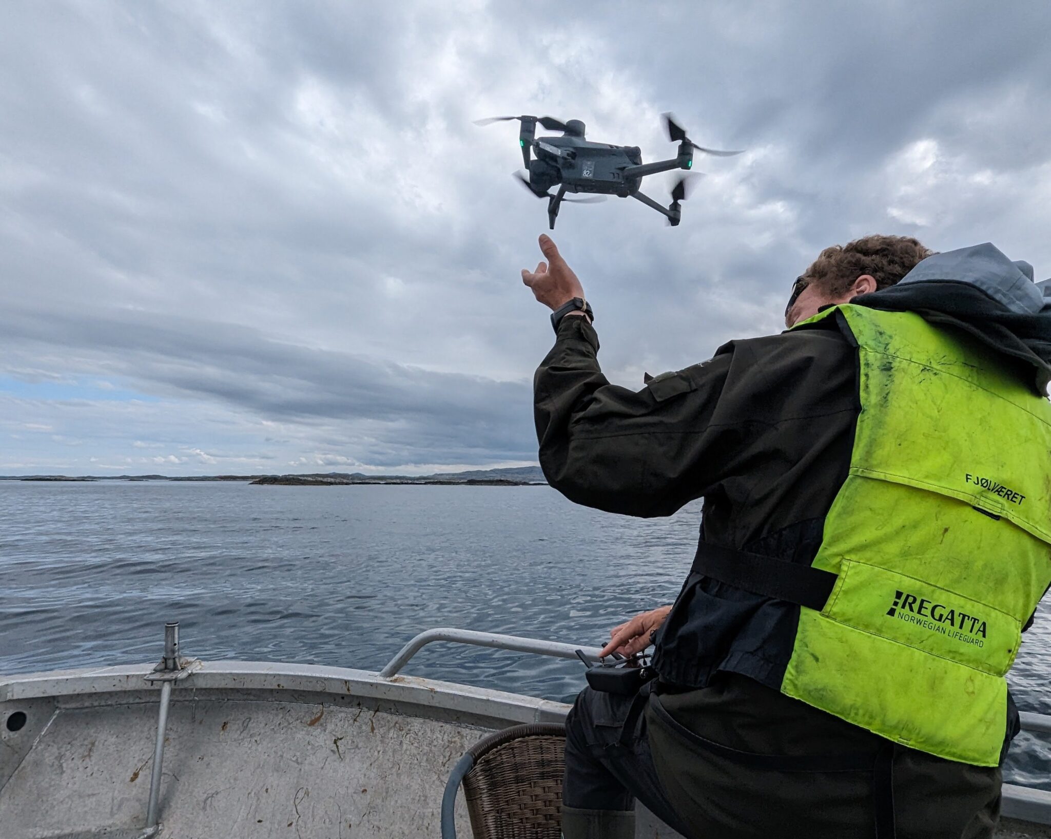 En feltarbeider sender opp en drone fra båt. Foto © Sindre Molværsmyr